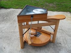 a wooden table with a metal bowl on top and a plate in the middle that is attached to it