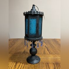 an old fashioned blue lantern sitting on top of a wooden table