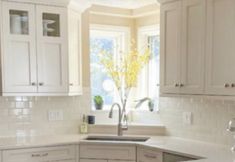 a kitchen filled with lots of white cabinets and counter top space next to a window