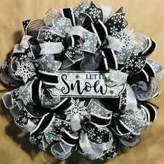 a black and white christmas wreath with let it snow written on the front in silver