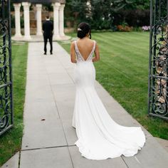 a woman in a white dress is walking down the sidewalk with her back to the camera