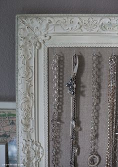 there are many necklaces on display in this white framed frame, which is hanging from the wall