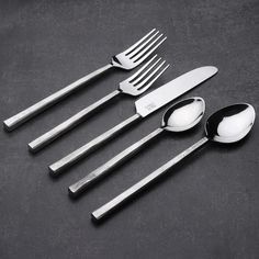 five spoons, two forks and one knife on a black surface with white lettering