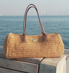 this beautful handmade bag is crocheted from %100 raffia in natural tone  and its very lightweight. Bohemian Handheld Straw Bag With Large Capacity, Bohemian Beach Satchel For Summer, Beach Woven Hobo Bag With Top Handle, Beach Woven Top Handle Hobo Bag, Bohemian Summer Satchel With Braided Handles, Woven Top Handle Hobo Bag For Beach, Summer Handheld Hobo Bag With Leather Handles, Elegant Straw Rectangular Bucket Bag, Natural Color Handheld Hobo Bag For Vacation