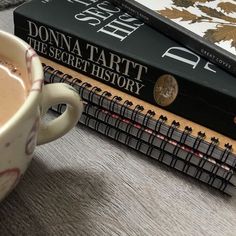 two books are stacked on top of each other next to a cup of hot chocolate