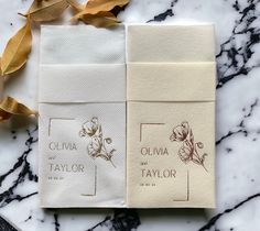 two folded towels sitting next to each other on a marble counter top with leaves around them