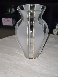 a glass vase sitting on top of a table next to a white cloth covered floor