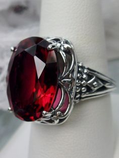 Art Deco Red Ruby Sterling Silver RingRetro Swirl Design#D119 Unlock the mysteries of the past and add a hint of vintage glamour to your jewelry wardrobe with Retro Swirl Ring. Constructed from 925 sterling silver, its intricate filigree swirls create an eye-catching Art Deco-inspired design – perfect for those looking to make a contemporary statement. Featuring a generously sized 18mm x 13mm Red Ruby gemstone in its prong setting, this ring sits 3/4" north south on your finger and 10mm off the Ornate Red Cabochon Jewelry, Elegant Oval Cabochon Ruby Ring For Wedding, Elegant Collectible Ring With Large Stone, Elegant Collectible Rings With Large Stone, Vintage Engraved Ruby Ring For Formal Occasions, Antique Oval Red Ruby Ring, Elegant Red Cabochon Ruby Ring, Elegant Jewelry With Oval Cabochon Garnet, Elegant Garnet Oval Cabochon Jewelry