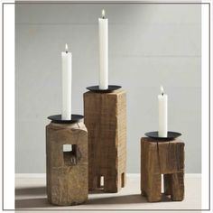 three wooden candle holders with white candles in them sitting on a table next to each other