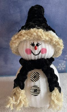 a knitted snowman wearing a black hat and scarf