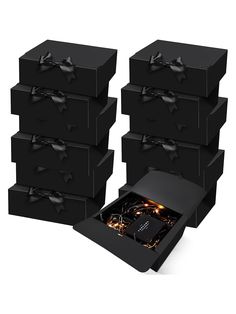 six black boxes with bows on them are stacked next to each other and one is open