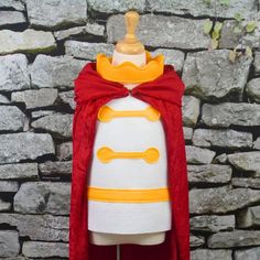 a white and red cape with yellow accents on top of a mannequin's head