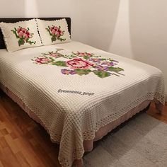 a bed with a white bedspread and pink flowers on the cover is shown