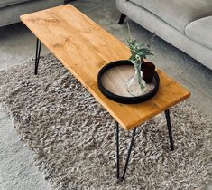 a wooden table sitting on top of a carpeted floor next to a gray couch