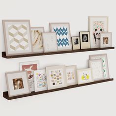 two wooden shelves with pictures on them and framed photos hanging from the wall behind them