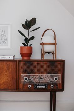 an old radio sitting on top of a wooden cabinet next to a potted plant