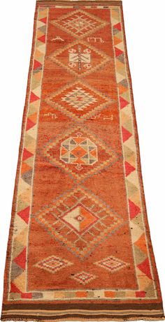 an orange, red and beige rug with geometric designs on the bottom half of it