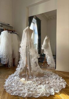 a wedding dress on display in front of a mirror with veils draped over it