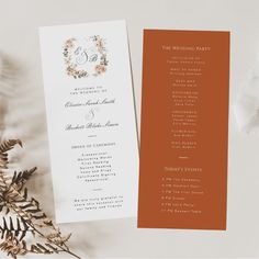 an orange and white wedding program on top of a table next to some pine cones