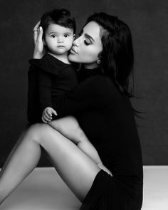 a woman holding a small child in her lap while sitting on top of a floor