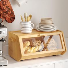 a counter with plates and cups on it next to a toaster, coffee maker and oven