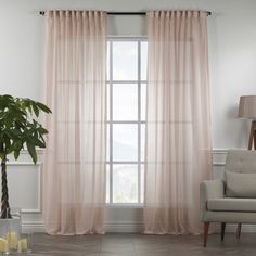 a living room with a couch, chair and window covered in pink sheer curtaines