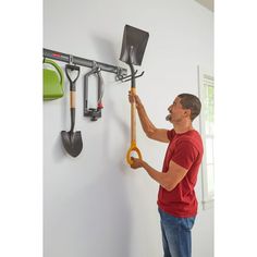 a man is working on a wall mounted garden tool rack