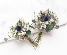 two bouquets of white and blue flowers on a marble surface