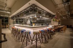 a bar with lots of stools next to it in a room filled with tables and chairs