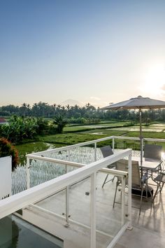 an outdoor dining area with umbrellas and chairs overlooking the rice fields at sunset or dawn