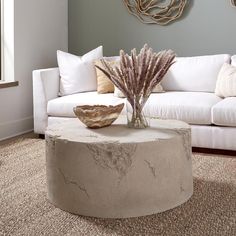 a living room with a white couch and coffee table in front of a painting on the wall