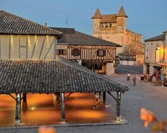 an old european town at dusk with people walking around the courtyard and buildings lit up