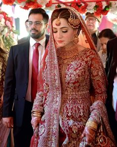 a woman in a red and gold bridal gown standing next to a man in a suit