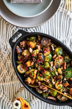 a pan filled with brussel sprouts and other vegetables on top of a table