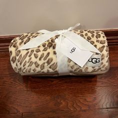 a leopard print blanket wrapped in white ribbon on top of a wooden floor next to a wall