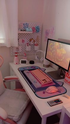 a desk with a computer monitor, keyboard and mouse pad on it next to a pink chair