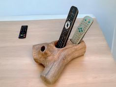 three remote controls are placed in a wooden holder on a table next to a tv remote control