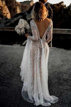 the back of a bride's dress with sequins on it and her bouquet