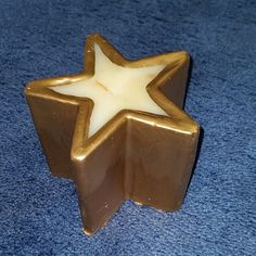 a brown and white star shaped candle holder on a blue carpeted floor with a light shining in the middle