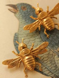 two gold bee brooches sitting on top of a blue and white paper towel