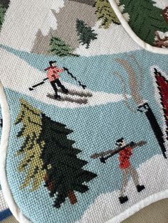 a close up of a cross stitch pattern on a blanket with people skiing and snowboarding