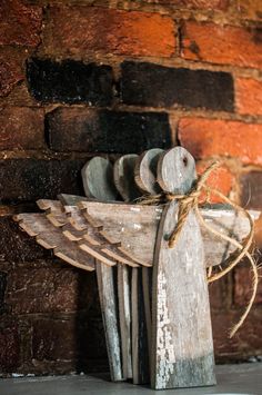 an angel made out of wooden sticks on top of a table next to a brick wall