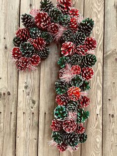 a wreath made out of pine cones on top of a wooden floor with red and green decorations