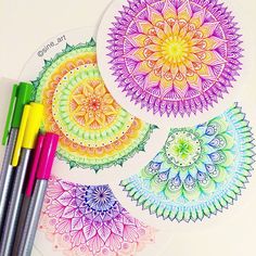 some markers and pens are sitting on top of a piece of paper with colorful designs