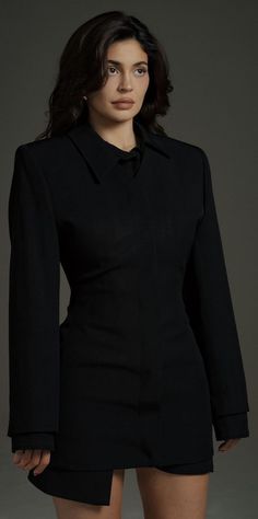 a woman in a black shirt dress posing for a photo with her hands on her hips