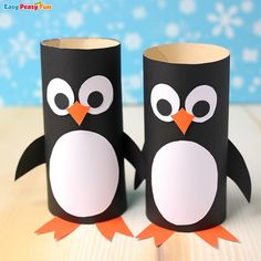 two toilet paper roll penguins sitting on top of a wooden table