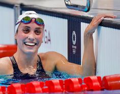 a woman in a swimming pool with goggles on and her arm around the edge