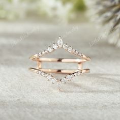 an open diamond ring sitting on top of a white surface next to a pine tree