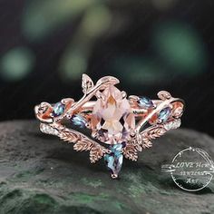 an engagement ring with pink and blue stones in the center on top of a rock