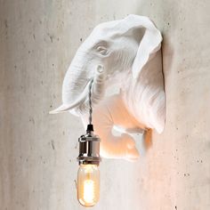 an elephant head hanging from the side of a wall with a light bulb attached to it